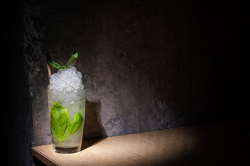 A cocktail with ice, basil and a straw