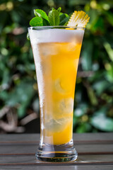 A cocktail with froth, ice, orange peel and mint