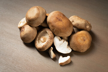 Multiple fresh shiitake mushrooms on wooden board