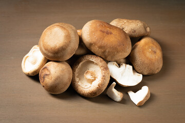 Multiple fresh shiitake mushrooms on wooden board