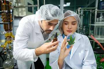 Selective focus of two scientists, Caucasian male and Asian female, in lab coats and bouffant caps,...