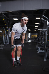 Fototapeta na wymiar Full length shot of a focused handsome athletic man working out with resistance band