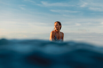 Attractive surfer woman in swimwear during surfing in ocean.