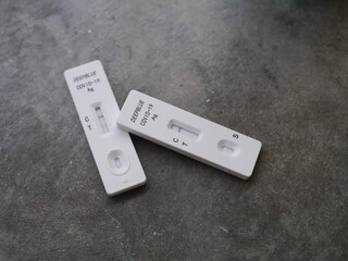Close-up photo of ATK test kit for Covid-19 testing positive and negative results placed on gray cement background suitable for illustration Bangkok Thailand, 15th July 2022