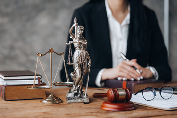 Goddess of justice and the judge's hammer are placed on the lawyer's table, lawyers consulting on various cases. To clients who are in trouble in the legal way. Lawyer concept and justice of the law.