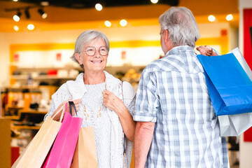 Obraz premium Happy senior couple carrying shopping bags enjoying shopping, consumerism sales customer shopping concept