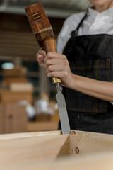 Carpenter uses hammer and chisel tools to work with wood in carpentry workshop