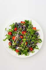 Light salad with arugula and berries, strawberries and blueberries, delicious healthy summer salad on a white background