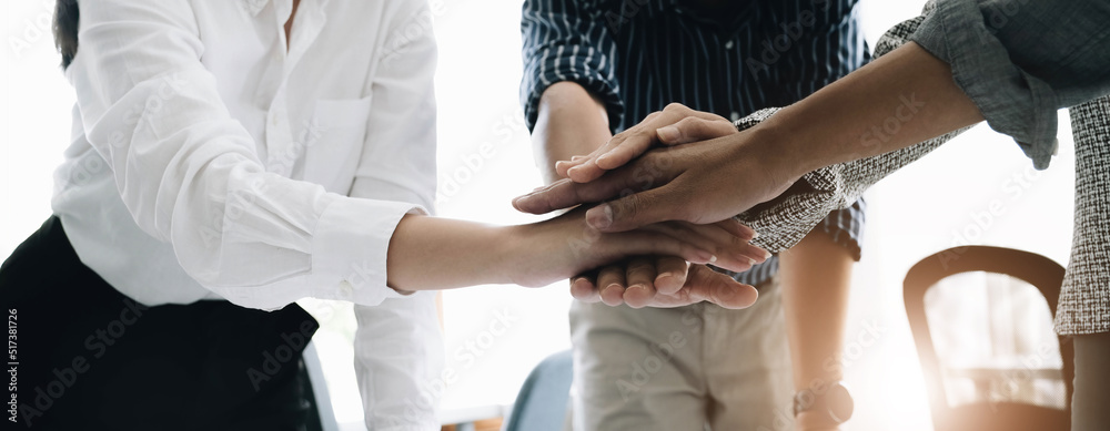 Wall mural Close up young business people putting their hands together. Stack of hands. Unity and teamwork concept.