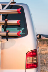 Rear vertical slanted image of a trunk door of a grey camper van equipped with a bike rack for 3...