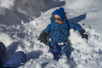 Smiling boy resting in the sun in a hole in the snow