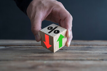 Businessman holds wooden blocks with percent and up or down arrow. Mortgage and loan rates....