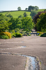 view of winding man-made pebbled stream meandering through wide footpaths in a botanical garden park