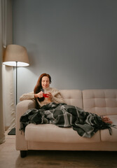 Young woman in a plaid drinks hot tea warming up after a frosty walk. The concept of a cold.