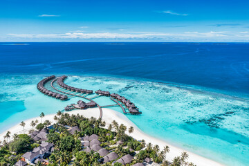 Aerial view of Maldives island, luxury travel water villas resort and wooden pier. Beautiful sky and ocean lagoon beach background. Summer vacation holiday. Paradise aerial landscape panorama - obrazy, fototapety, plakaty