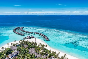 Crédence de cuisine en verre imprimé Bleu Aerial view of Maldives island, luxury travel water villas resort and wooden pier. Beautiful sky and ocean lagoon beach background. Summer vacation holiday. Paradise aerial landscape panorama