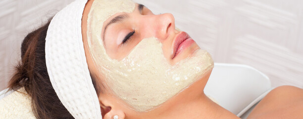 Girl with facial mask lying in beauty health spa center