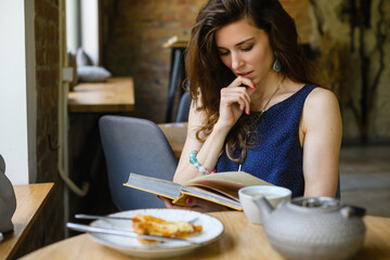 Girl reading a book while having breakfast in a coffee shop