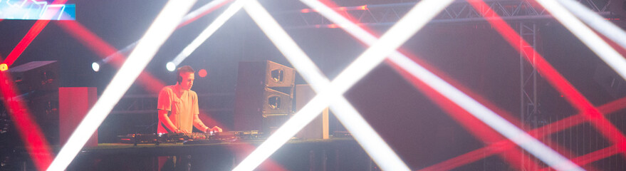 Dj playing techno music on the stage at night summer concert
