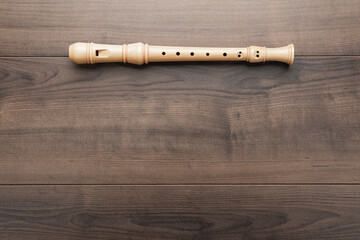 Overhead photo of block flute with copy space. Flat lay top-down composition of wooden recorder on the wooden background.