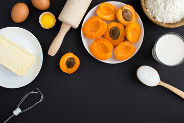 Top view of ingredients for making apricot pie or cake on the black background. Copy space.