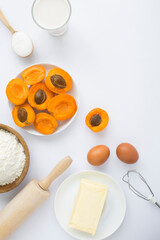 Top view of ingredients for making apricot pie or cake on the white background. Copy space. Location vertical.