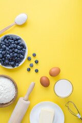 Top view of ingredients for making blueberry pie or cake on the yellow background. Copy space. Location vertical.