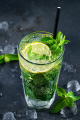 mojito cocktail with mint, ice and lemon. Fresh cocktail in glass on dark background