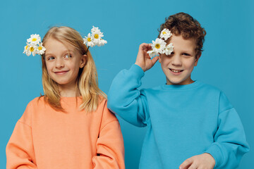 beautiful, happy children brother and sister, of school age, stand on a plain blue background in...