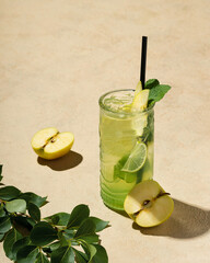 Apple juice, apple cocktail garnished with apple slices, in a glass on a sand-color background