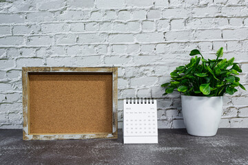 July 2022 white calendar with wooden frame and potted plant on wooden desk.