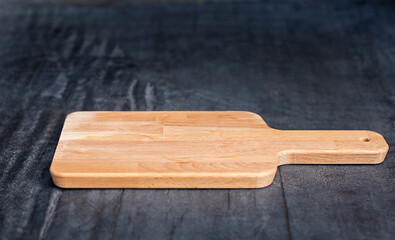 empty wooden cutting board on black background close up