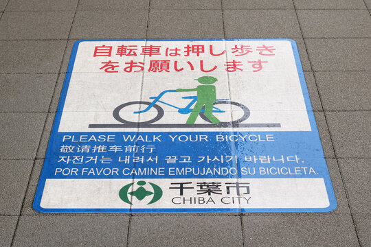 CHIBA, JAPAN - September 9, 2021:  Multi-lingual notice on a sidewalk in Chiba City asking cyclists to push thir bikes.