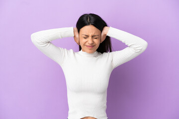 Young caucasian woman isolated on purple background frustrated and covering ears