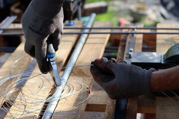 Man holds pliers and steel wire. Handyman tools close up photo. Male hands in grey protective gloves. 