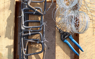 Steel wire and blue pliers close up photo. Craftsman tools on a worktable. 