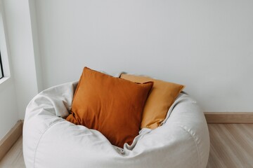 Brown pillows and beanbag sofa in white room next to the window