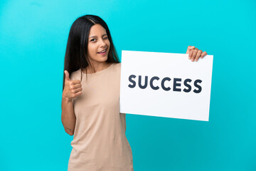 Young woman over isolated background holding a placard with text SUCCESS and pointing to the front