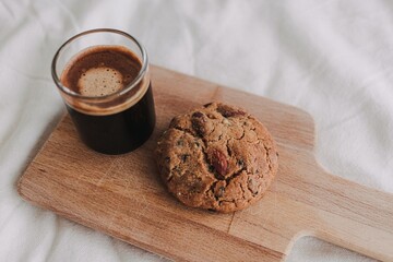 Hot espresso coffee served with homemade cookies on wooden board.