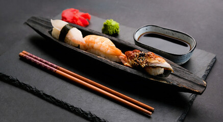 Elegant sushi sashimi set composition with fresh shrimp and raw salmon served with ginger, wasabi and soy sauce. Traditional japanese meal on black table with wooden chopstick © Ievgen Skrypko