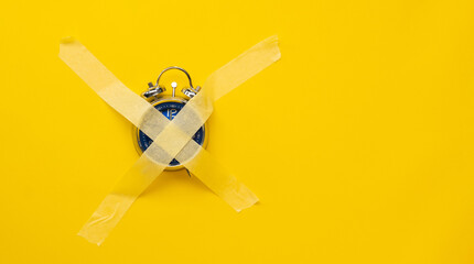 Naklejka na ściany i meble Blue clock sticked up crosswise with masking tape isolated on yellow background with copy space. Concept of timeless things in life, deficiency of time. Weekend morning without work hours