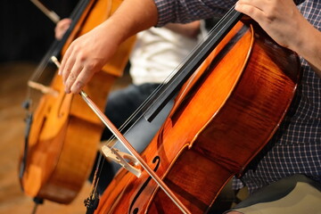 Symphony orchestra on stage, hands playing cello. Professional cello player's hands close up, he is...