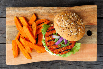 Healthy, plant based burger with sweet potato fries. Top view against a wood background.