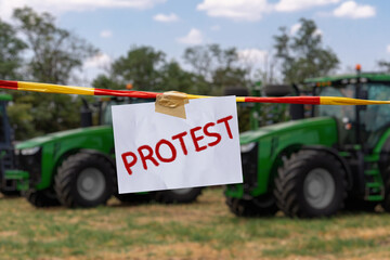 The inscription PROTEST on the background of tractors. Farmers protest symbol.