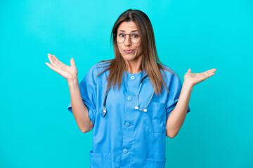 Middle age surgeon woman isolated on blue background having doubts while raising hands
