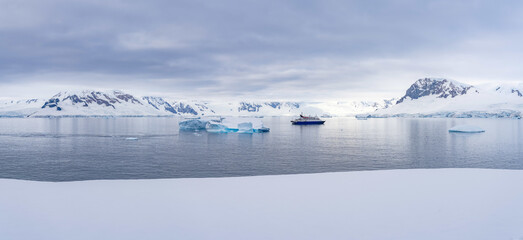 Expeditionsschiff vor antarktischer Eisberg Landschaft bei Portal Point welches am Zugang zu Charlotte Bay auf der Reclus Halbinsel, an der Westküste von Graham Land liegt.	