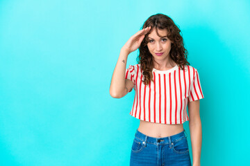 Fototapeta na wymiar Young woman with curly hair isolated on blue background saluting with hand with happy expression