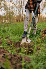 a woman digs the ground with a shovel for planting a plant in the country
