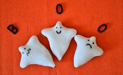 Halloween cookie in the shape of a ghost on an orange background and with the text 