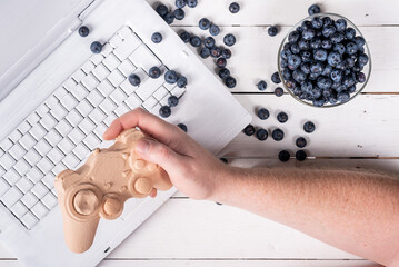 freelancer plays a joystick on a white background and blueberries. trend colors